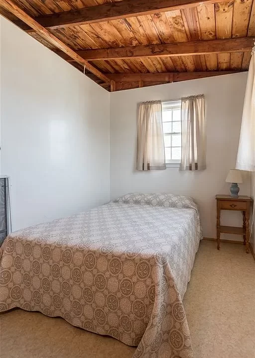 a bed sitting under a wooden ceiling in a bedroom.