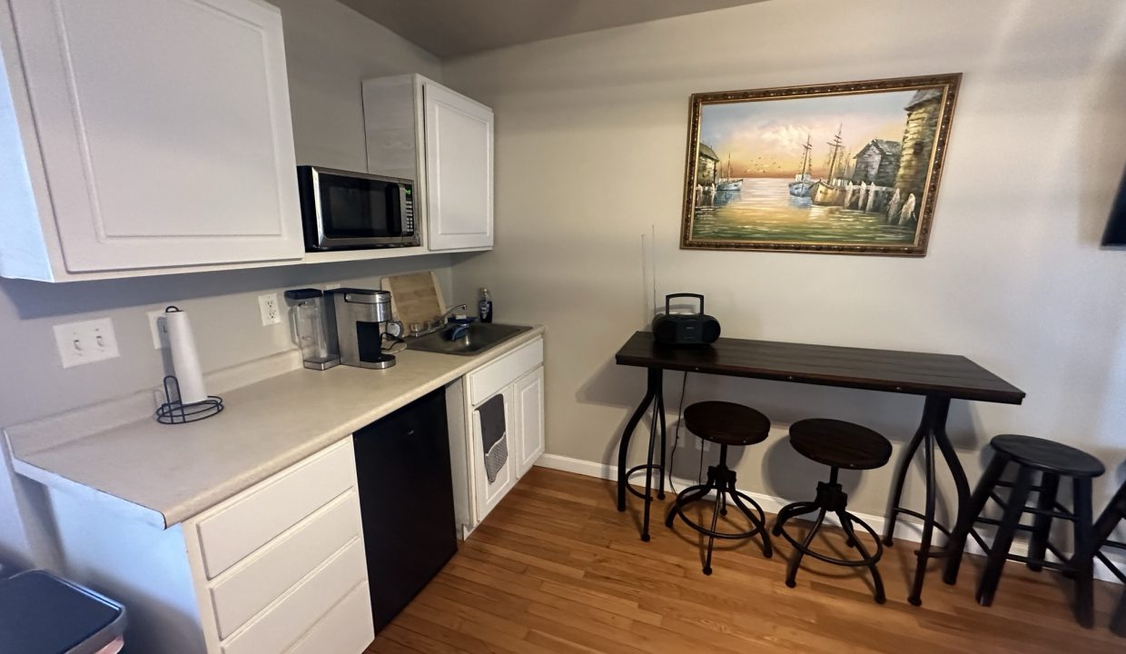 a kitchen with white cabinets and black stools.