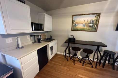 a kitchen with white cabinets and black stools.