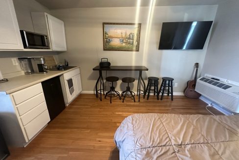 a bed sitting in a bedroom next to a kitchen.