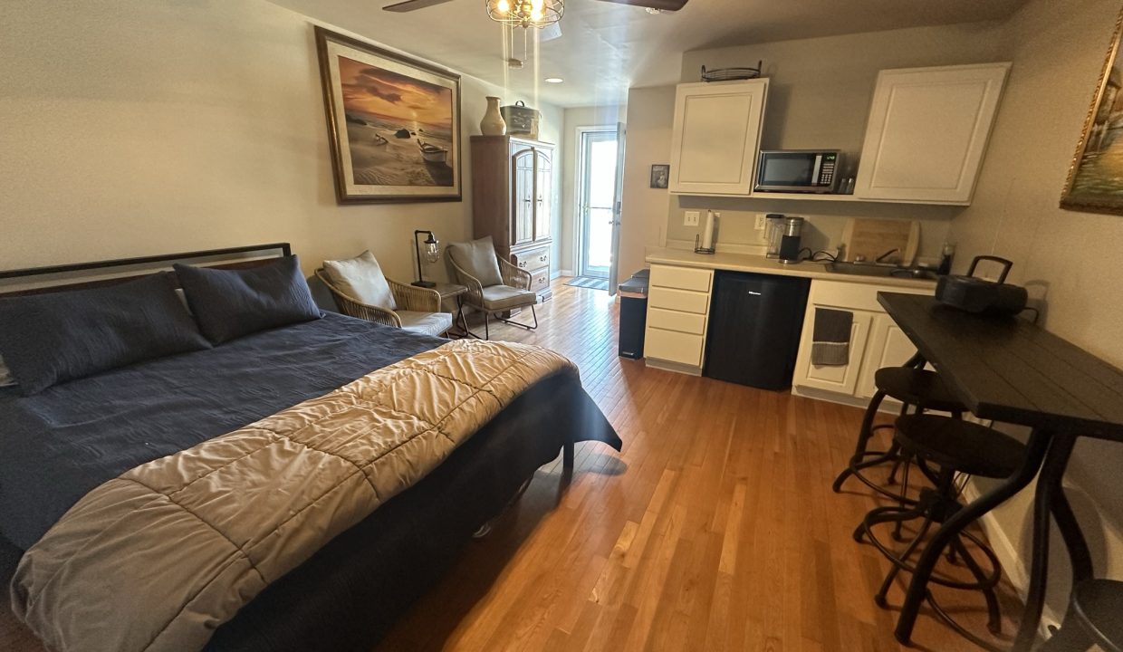 a bed sitting in a bedroom next to a kitchen.