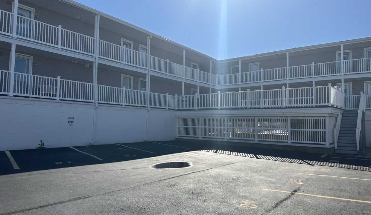 an empty parking lot in front of an apartment building.