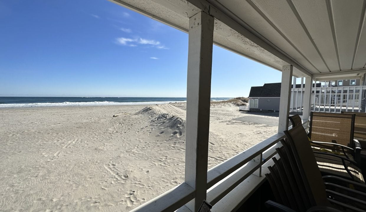 a view of the beach from a covered porch.