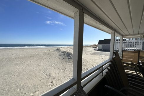 a view of the beach from a covered porch.