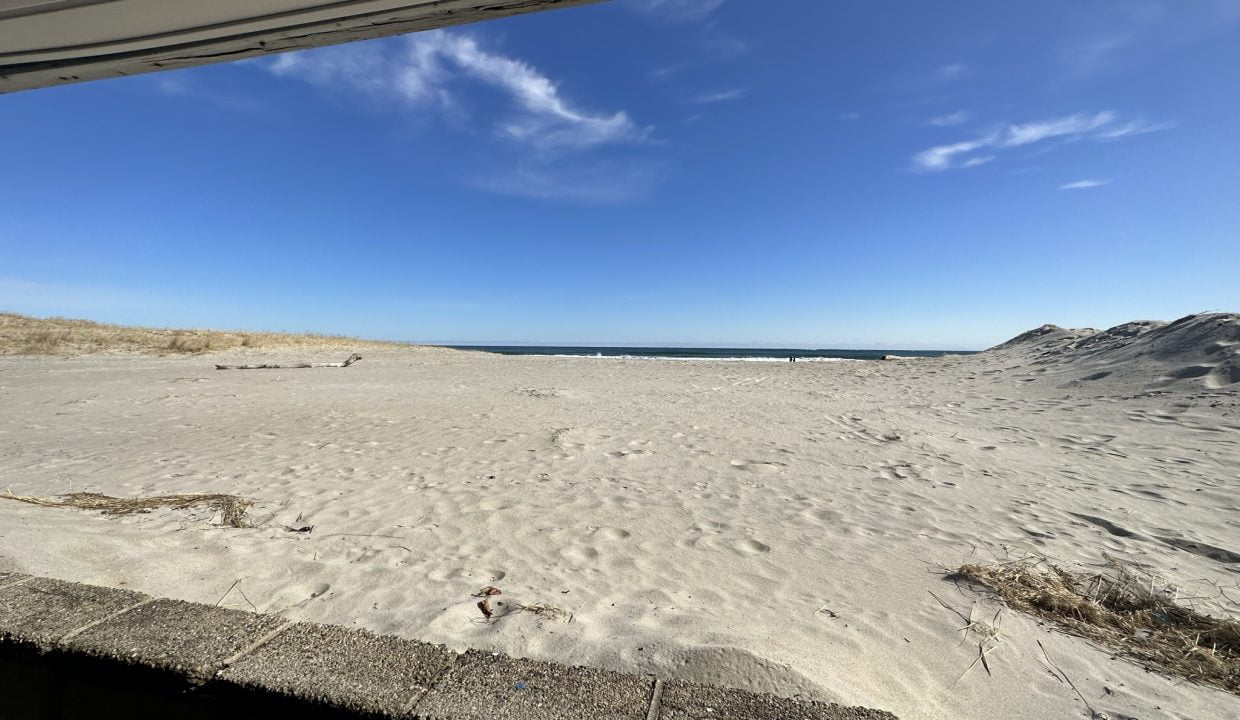 a sandy beach with a blue sky and some clouds.