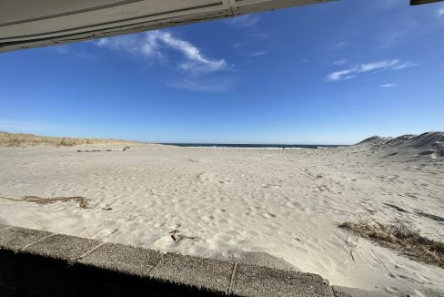 a sandy beach with a blue sky and some clouds.