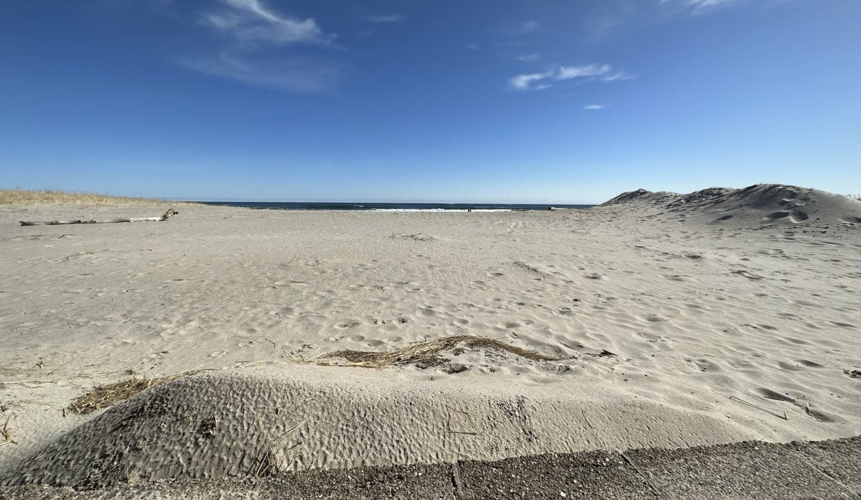 a sandy beach under a blue sky with clouds.