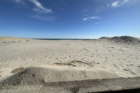 a sandy beach under a blue sky with clouds.