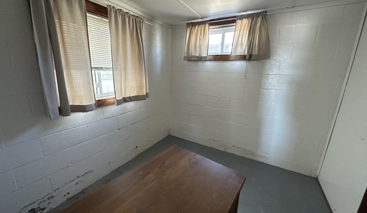 a room with a wooden table and two windows.