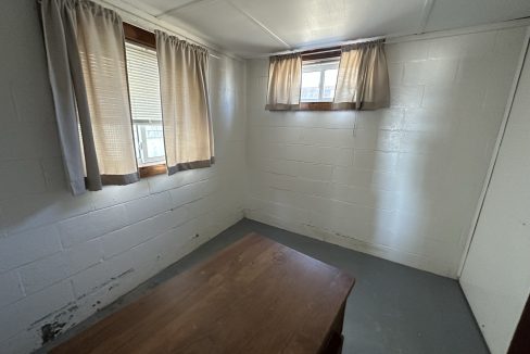 a room with a wooden table and two windows.