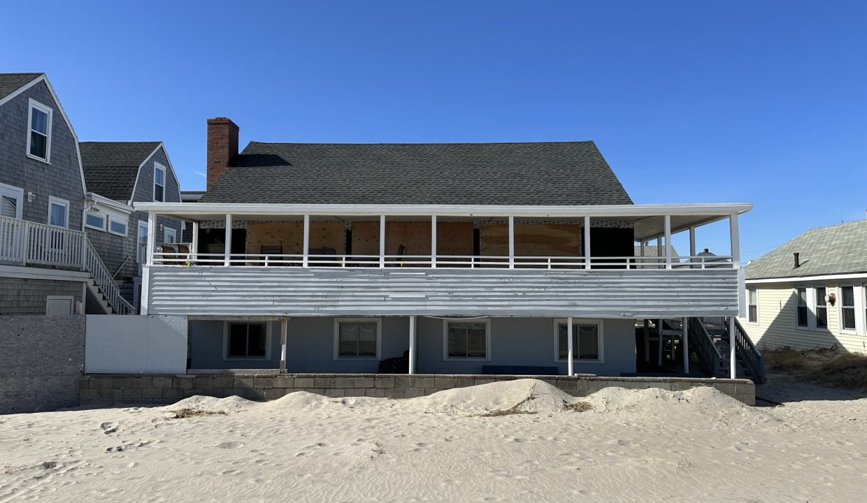 a beach house with a balcony and sand dunes.