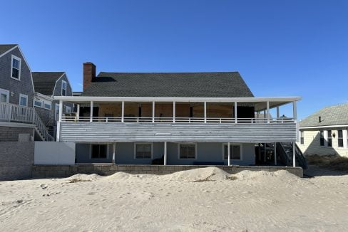 a beach house with a balcony and sand dunes.