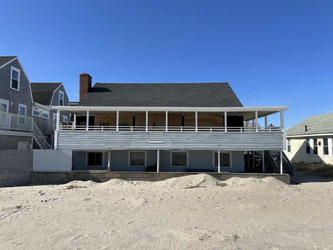 a beach house with a balcony and sand dunes.