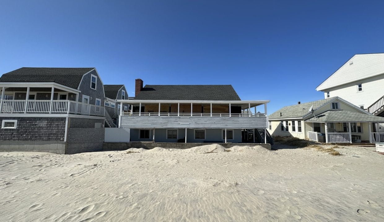 a house on a beach with sand in front of it.