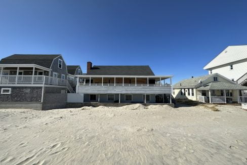 a house on a beach with sand in front of it.