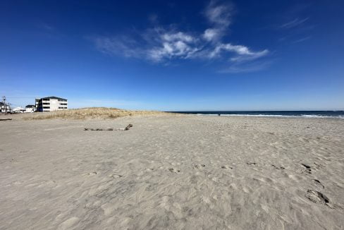 a sandy beach with a house in the distance.