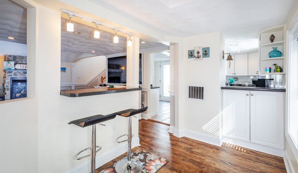 a white kitchen with a bar and stools.