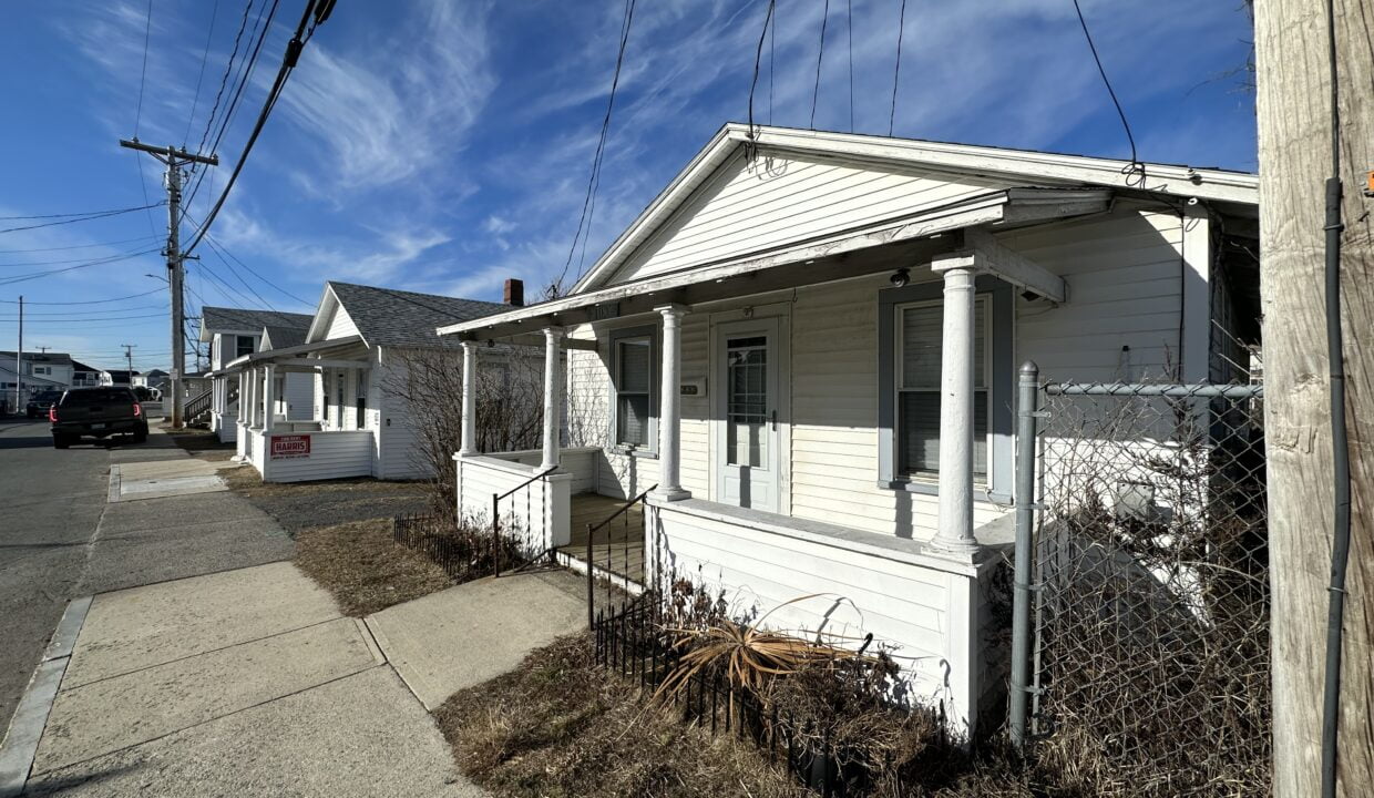 a small white house sitting next to a street.
