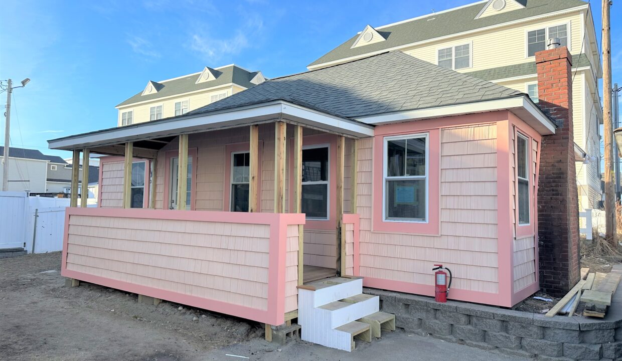 a small pink house with a porch and stairs.