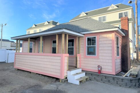 a small pink house with a porch and stairs.