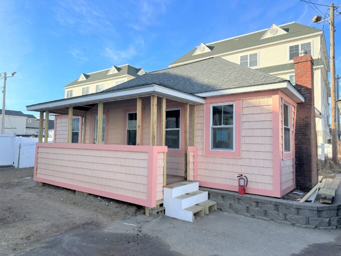 a small pink house with a porch and stairs.