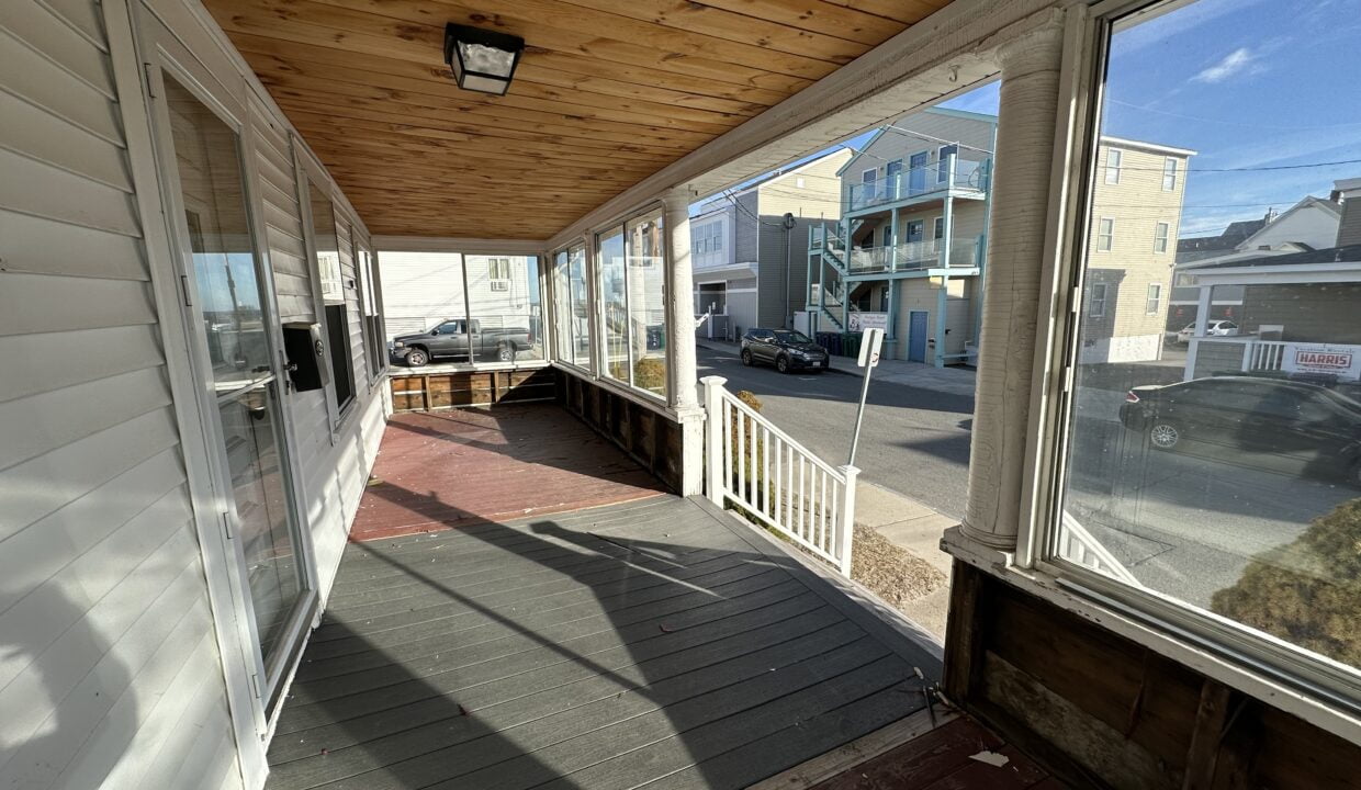 a porch with a wooden ceiling and a light fixture.
