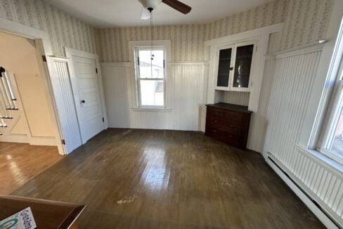 an empty room with a ceiling fan and hard wood floors.