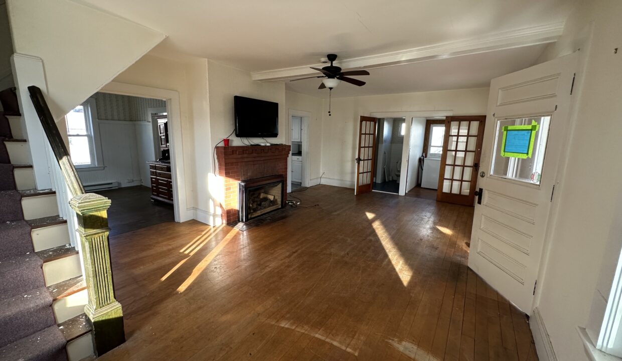 a living room with hard wood floors and a ceiling fan.