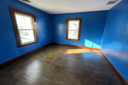 a empty room with blue walls and wooden floors.