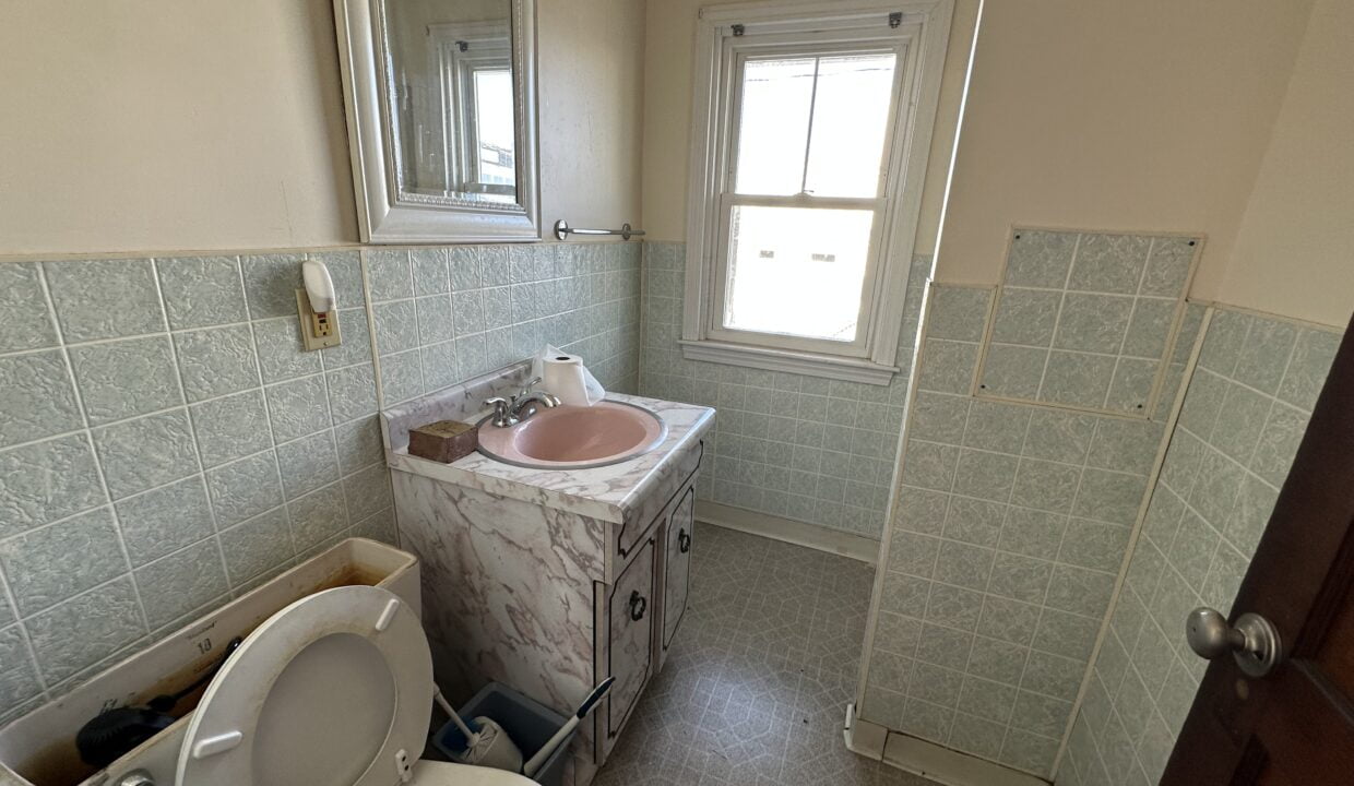 a bathroom with a toilet, sink, and mirror.