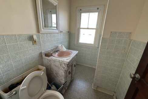 a bathroom with a toilet, sink, and mirror.