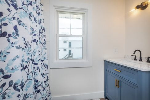 a bathroom with blue cabinets and a blue shower curtain.
