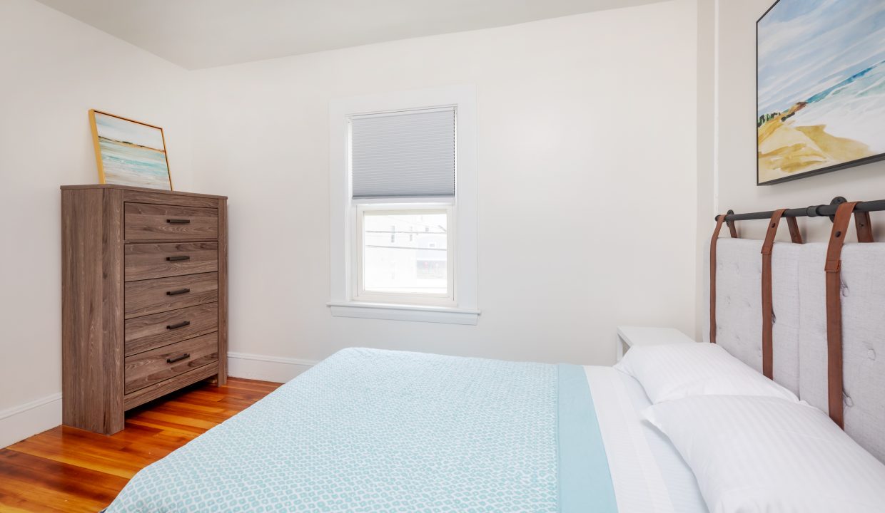 a bedroom with hardwood floors and a blue comforter.