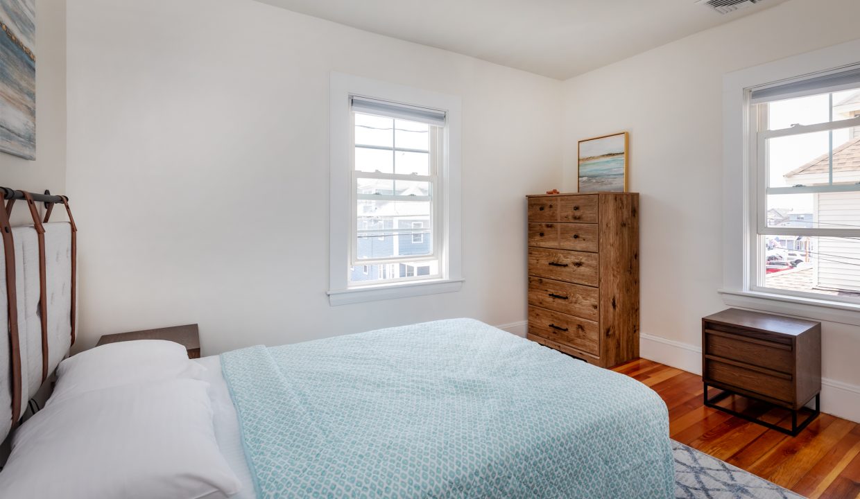 a bedroom with hardwood floors and a blue comforter.