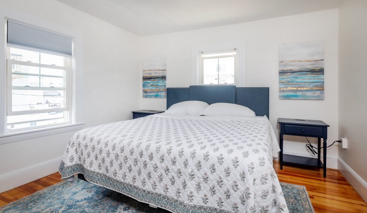 a bed in a bedroom with white walls and a blue rug.