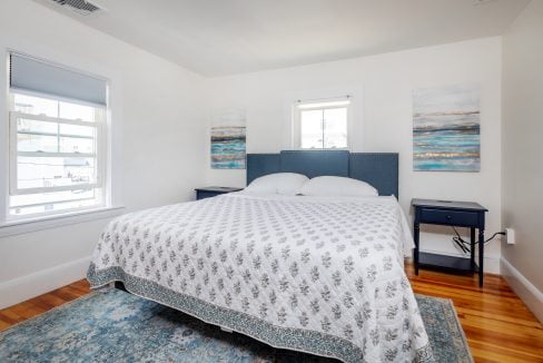 a bed in a bedroom with white walls and a blue rug.