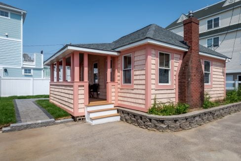 A small pink house with a porch and steps.
