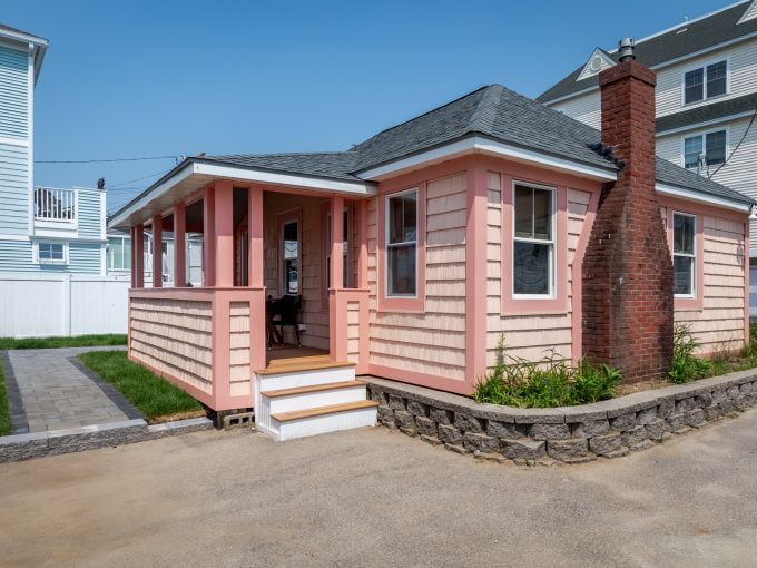 A small pink house with a porch and steps.