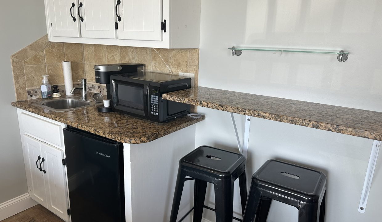 a kitchen with a microwave and two stools.