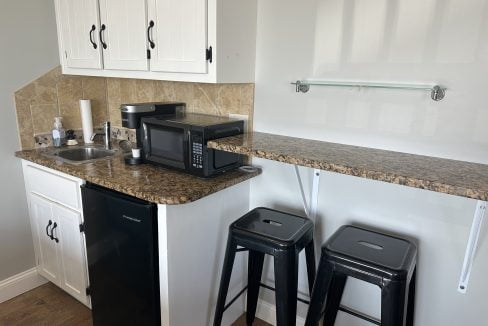 a kitchen with a microwave and two stools.