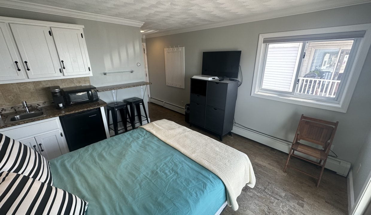 a bed sitting in a bedroom next to a kitchen.