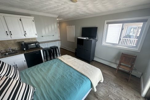 a bed sitting in a bedroom next to a kitchen.
