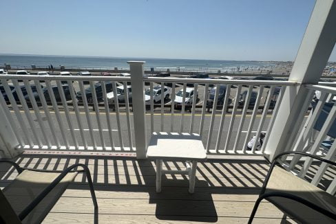 a chair and table on a deck with a parking lot and a beach.