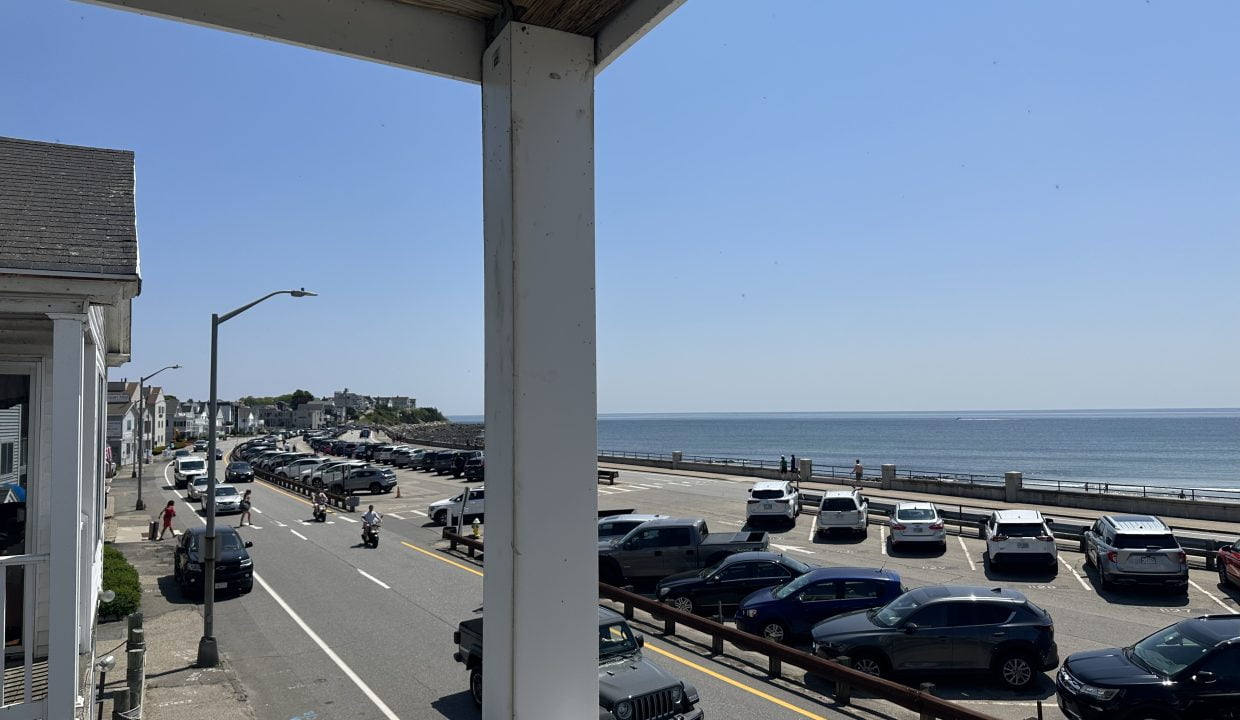a view of a road with cars and a body of water from a balcony.