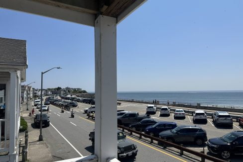 a view of a road with cars and a body of water from a balcony.