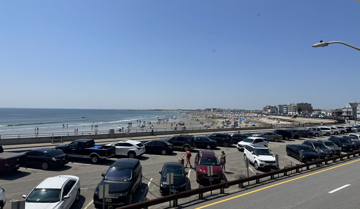 a parking lot filled with lots of cars next to the ocean.