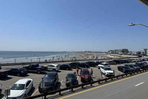 a parking lot filled with lots of cars next to the ocean.