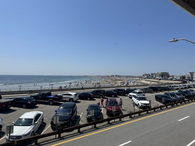a parking lot filled with lots of cars next to the ocean.