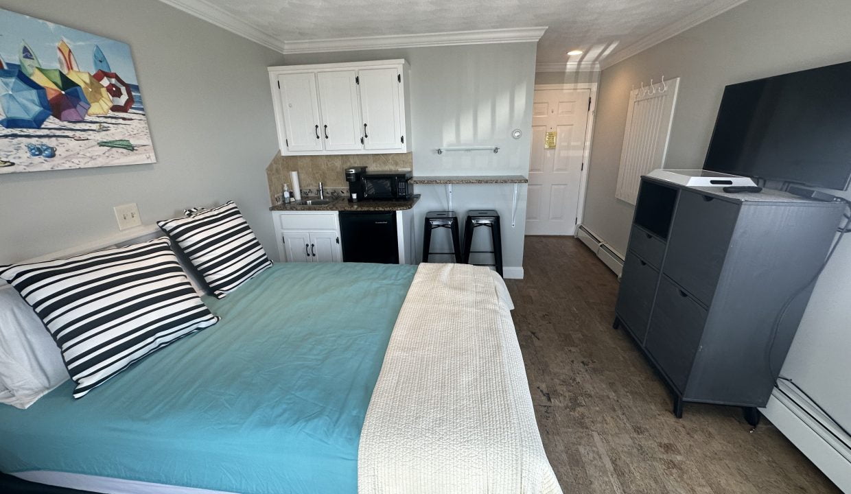 a bed sitting in a bedroom next to a refrigerator.