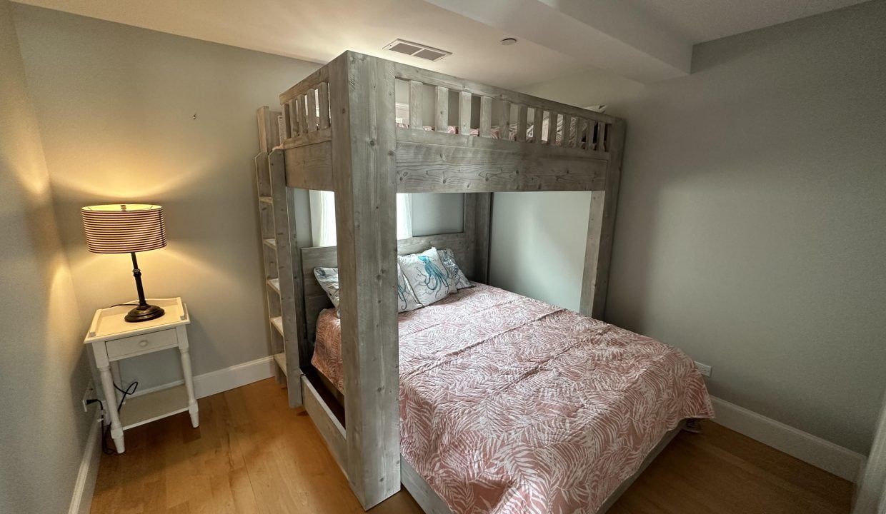 a bedroom with a bunk bed with a pink bedspread.